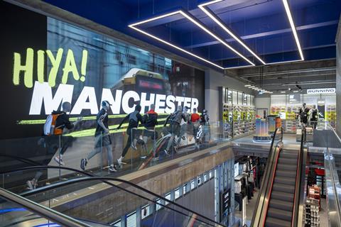 Interior of Sports Direct Manchester store showing escalator and sign saying: 'Hiya Manchester!'